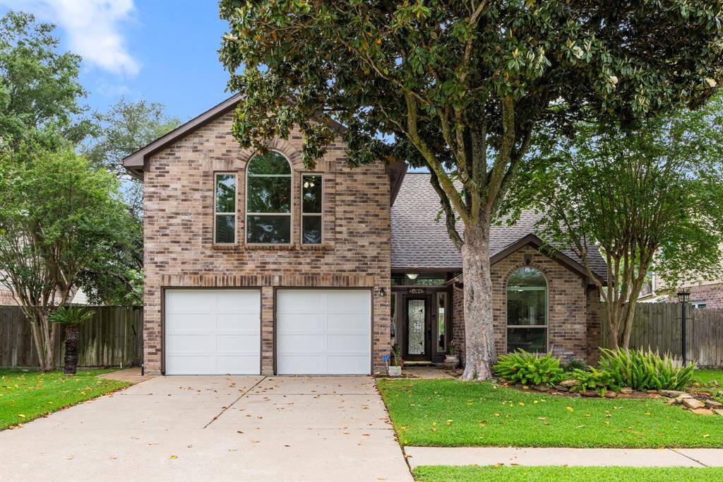Charming two-story brick home with a double garage. The front yard features mature trees and well-maintained landscaping. Large arched windows add character and provide ample natural light. A welcoming entrance enhances curb appeal.