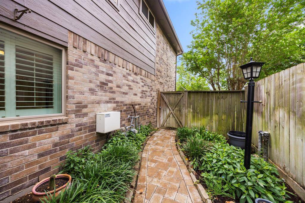 Charming outdoor side area with a paved walkway provides easy trash can storage out of site (not pictured here). Shown here is also the main hub of the mosquito misting system.