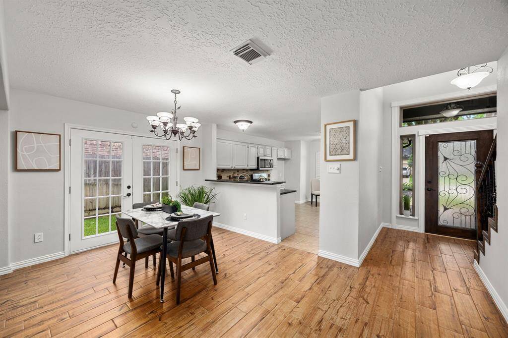This inviting home features a bright, open dining area with wood look tile flooring and elegant French doors leading to the backyard. The adjacent kitchen offers freshly painted cabinetry and a cozy, intimate feel.