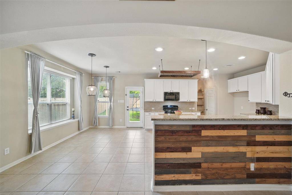The kitchen has lots of natural light and decorative light fixtures.