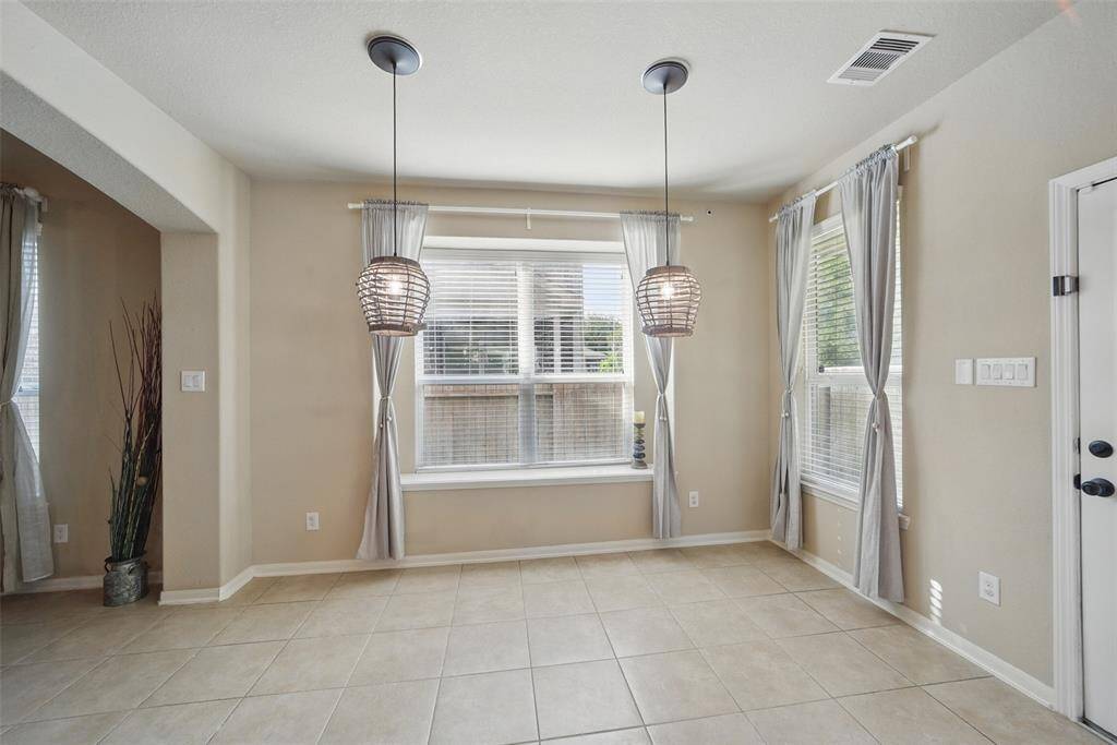 This dining space has decorative pendant lighting and cozy curtains.