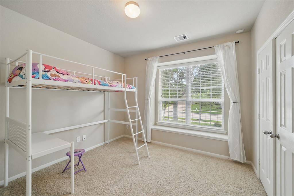 The front bedroom is roomy with french doors on the closet and curtains for the windows.