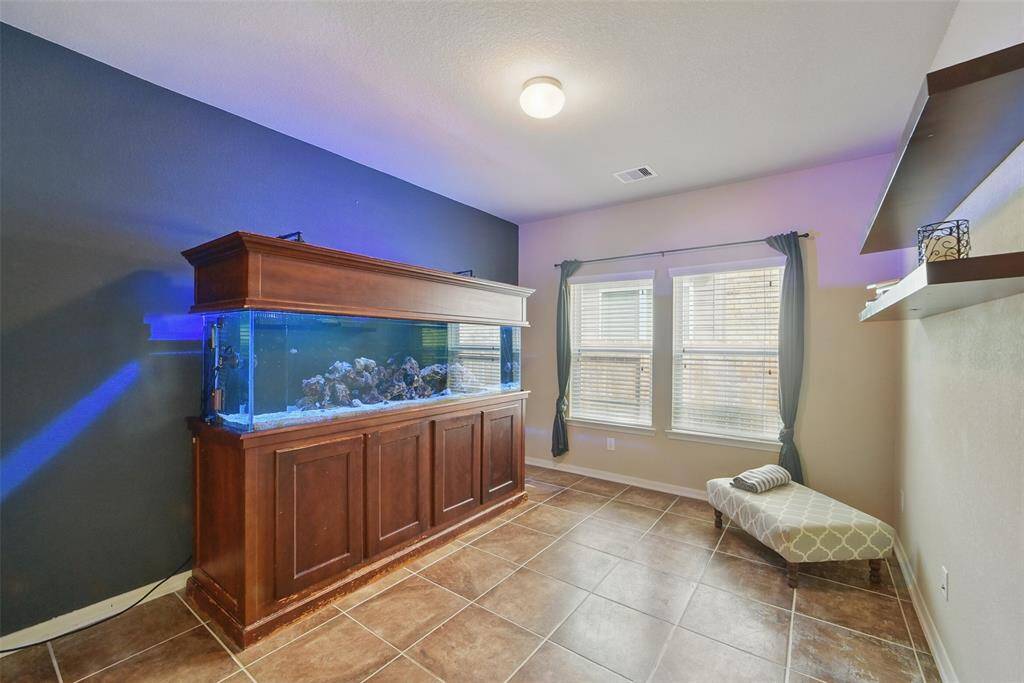 The study features tile flooring, window coverings and floating shelves.  The aquarium stays, if desired.