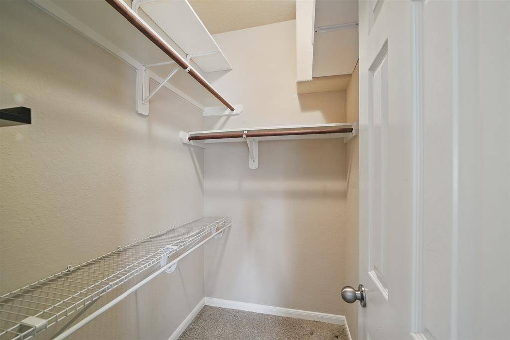 The closet in the primary bedroom has plenty of shelves and racks.