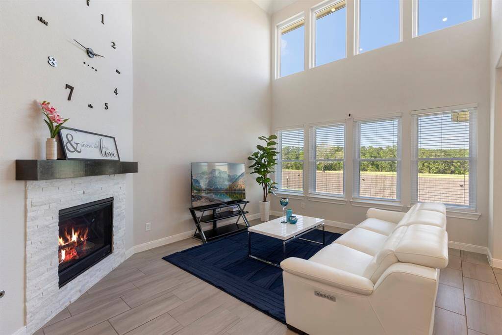Showing off the home's natural light, the family room also highlights a two story ceiling and a stacked stone fireplace.