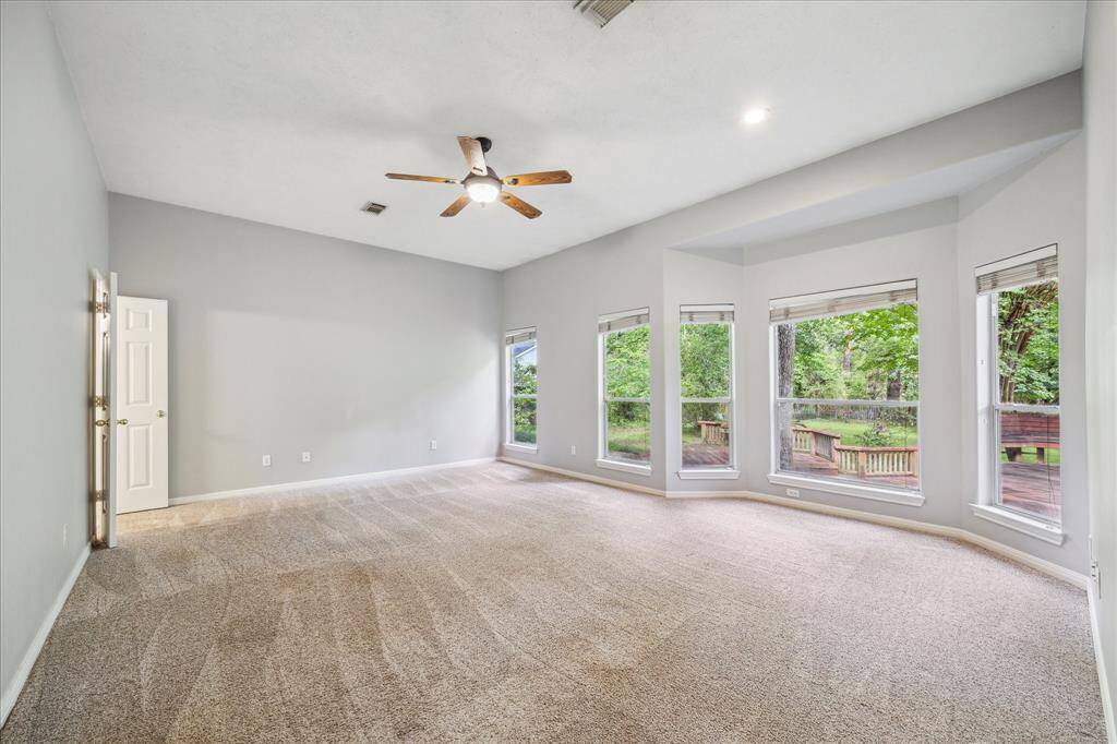 Welcome to your spacious primary retreat, featuring a wall of windows that frame peaceful views of the expansive backyard and the untouched land beyond.