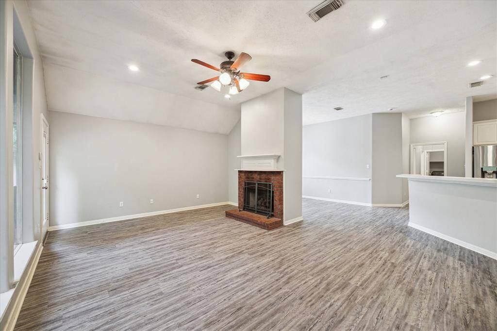From the living room, enjoy a seamless view into the kitchen and breakfast nook. A centrally positioned fireplace creates a natural separation between the spaces while adding a stylish and inviting focal point.