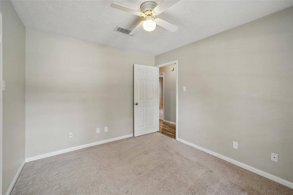Secondary bedroom with plush carpet & ceiling fan.