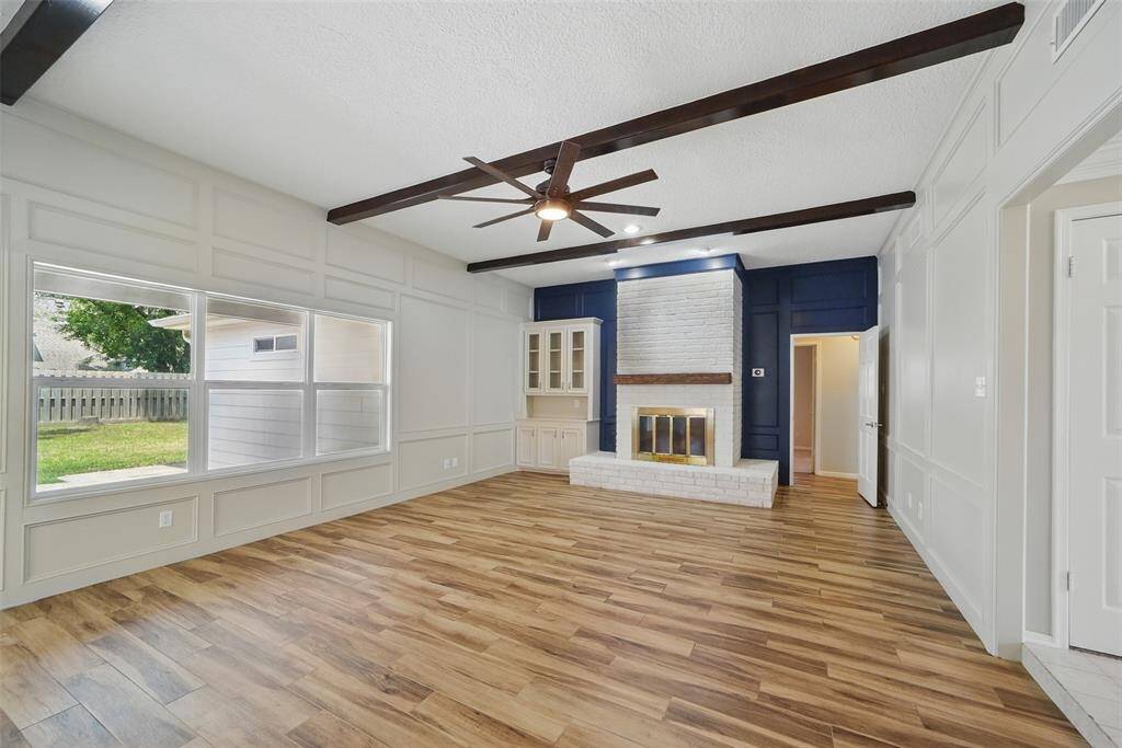 The living room has lots of natural light, gas fireplace, built-ins and custom painted wood paneling.