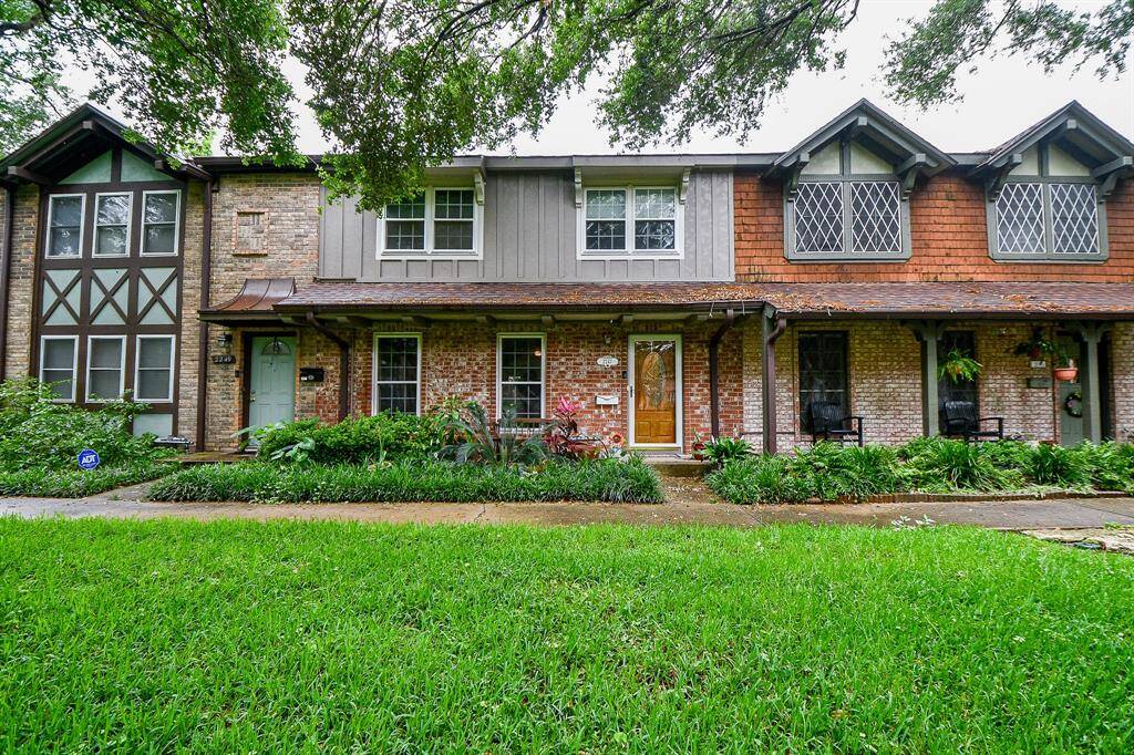 This charming townhouse features a classic facade with brick and wood detailing, a welcoming front porch, and lush landscaping. The home offers a cozy, traditional feel in a well-maintained neighborhood setting.
