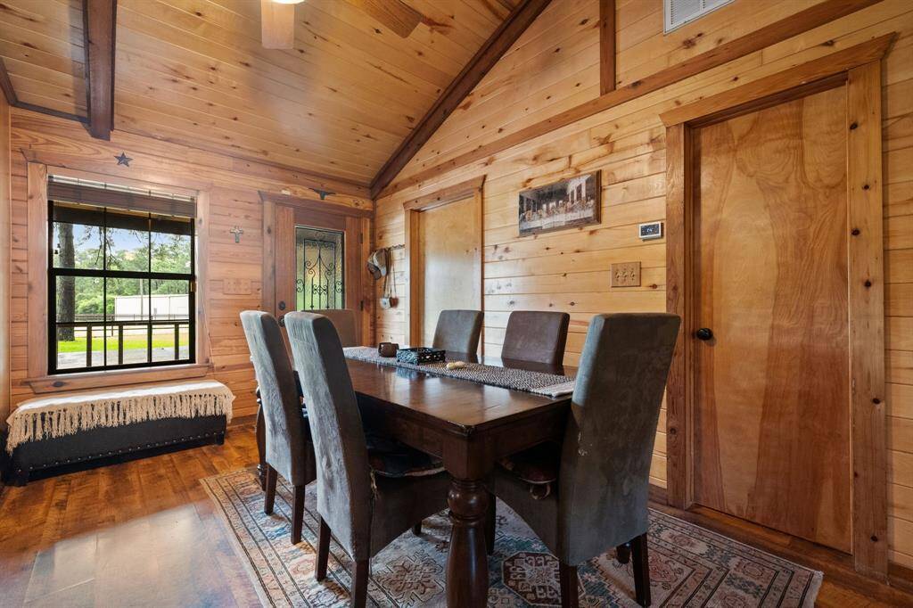 A cozy dining area with warm wood paneling and a vaulted ceiling.  The room has a rustic charm, enhanced by natural light and decorative elements.