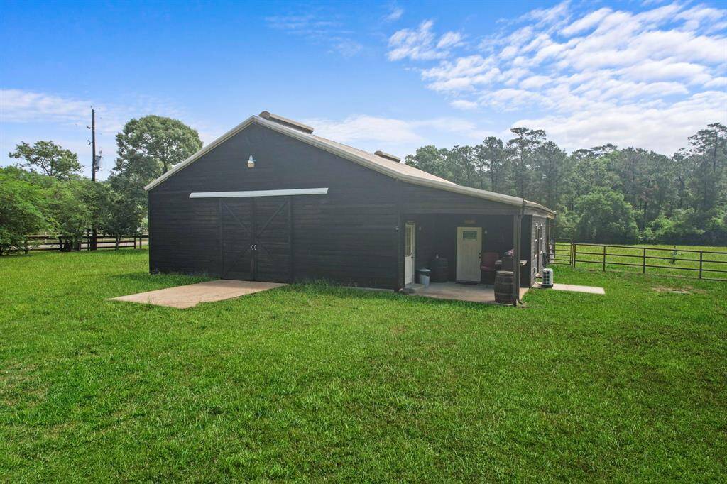 A charming barn on a spacious, well-maintained grassy property, surrounded by trees and open fencing, ideal for equestrian or agricultural use.