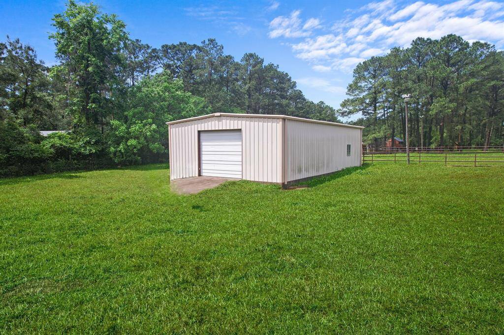 A well-maintained grassy yard with a large metal storage building, surrounded by trees, offering a serene and private setting.