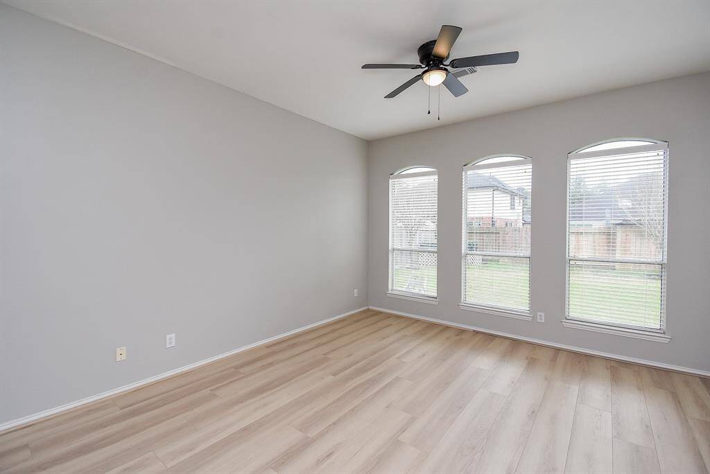 A bright, spacious primary bedroom features three large windows providing plenty of natural light and offer a view of the backyard.