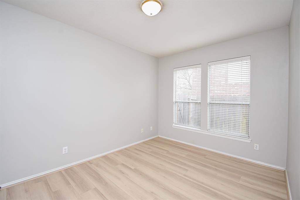 This second bedroom down features light flooring, neutral color walls, and two large windows providing natural light. It has a clean, modern look, ideal for personalizing as a bedroom or nursery or craft room or gym.