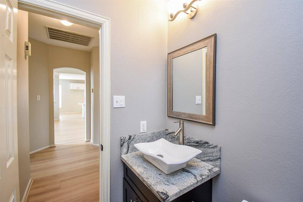 Discover a sleek bathroom featuring a vessel sink on a granite countertop, complemented by a stylish framed mirror and modern faucet.