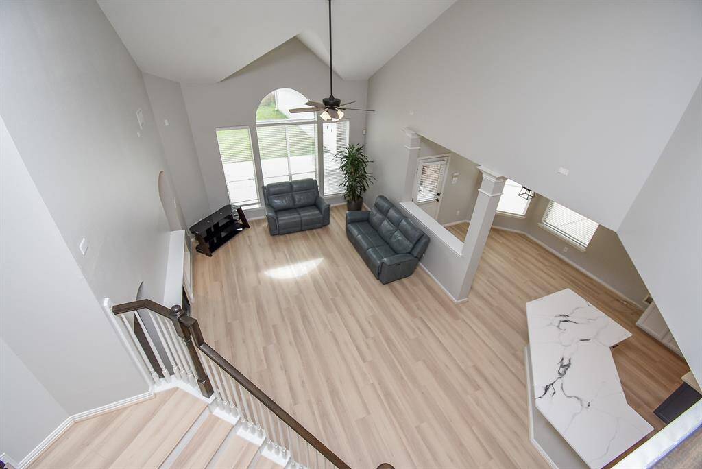 This photo showcases a bright, open-concept living space with high ceilings and large windows. The room features light flooring and a sleek kitchen area with quartz countertop. Perfect for a contemporary and spacious home environment.
