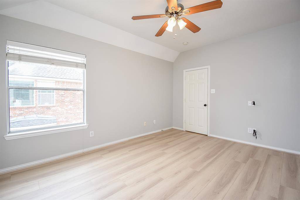 Bright secondary bedroom features a window with blinds, fan and a closet.