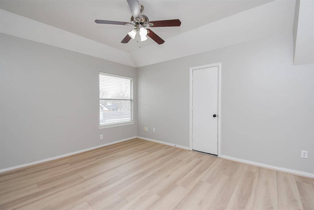 This room features light flooring and neutral walls, creating a bright and airy atmosphere. It has a large window with blinds, allowing for plenty of natural light. The ceiling light fixture adds a simple yet functional touch.