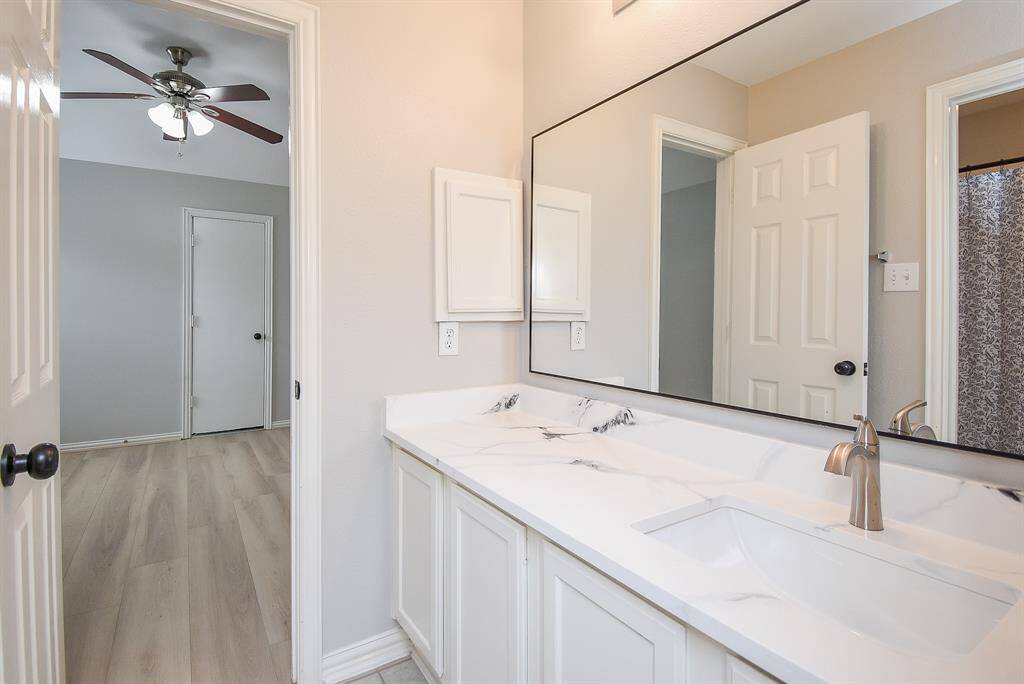 This photo features a modern Hollywood bathroom with a sleek, white quartz countertop and a sink. There's a large mirror above the sink.
