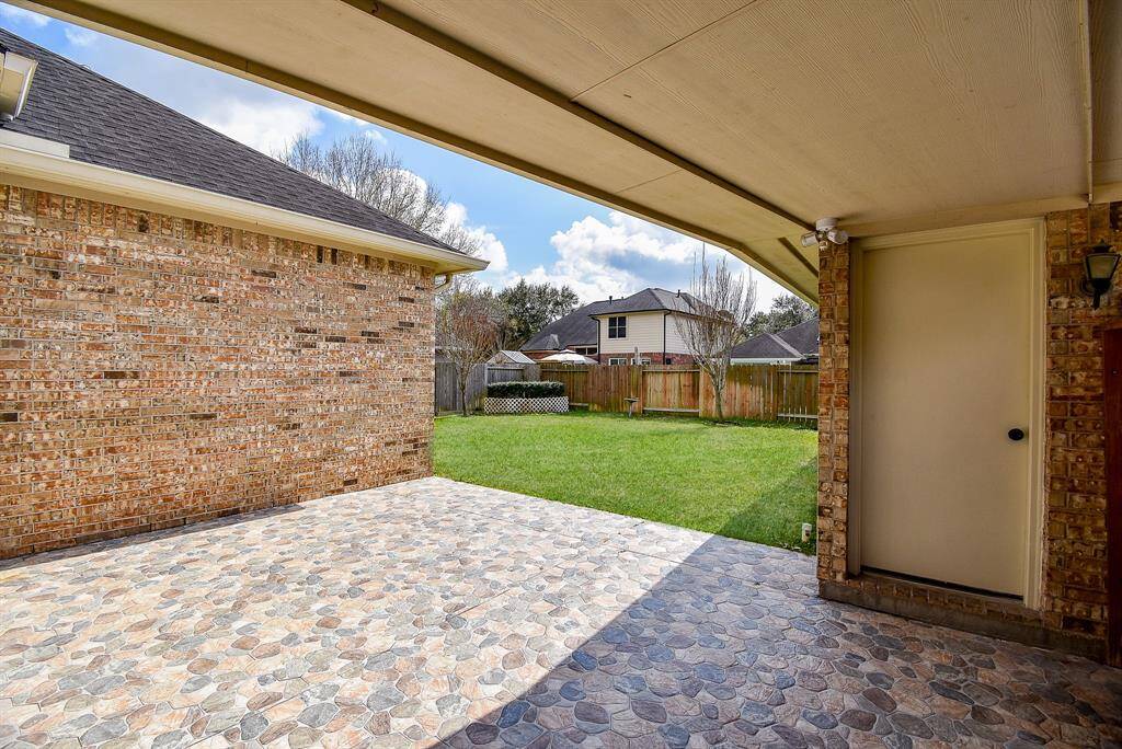 This photo showcases the patio with tile flooring. It opens to a spacious, fenced backyard, offering a versatile outdoor space.