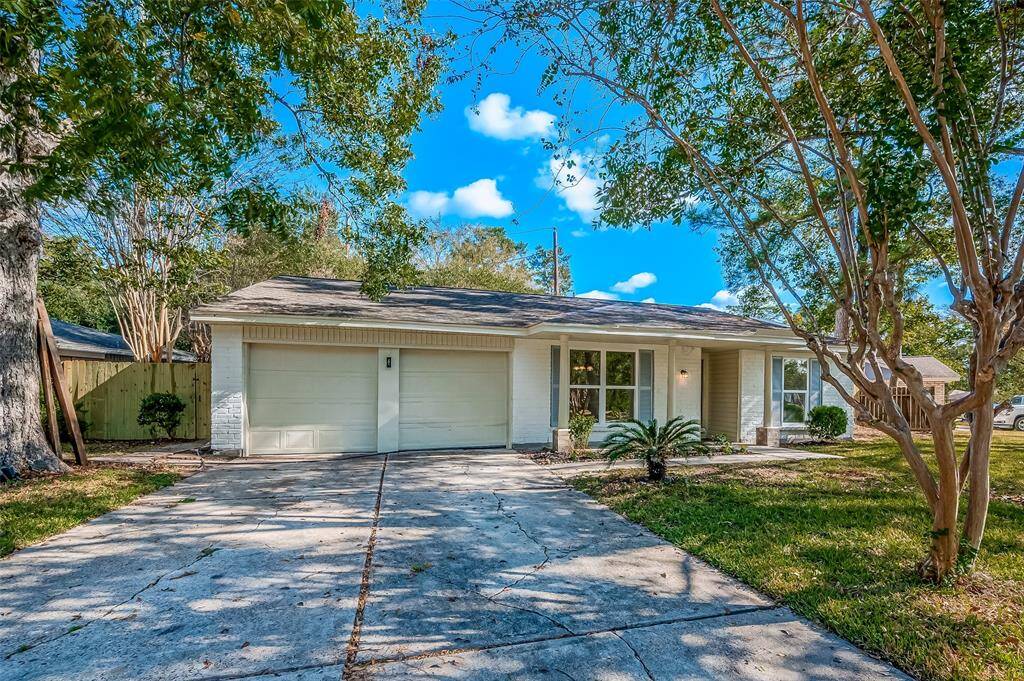 Single-story home with a clean, painted brick facade, an attached garage, and a welcoming front porch nestled in a neighborhood with mature trees.