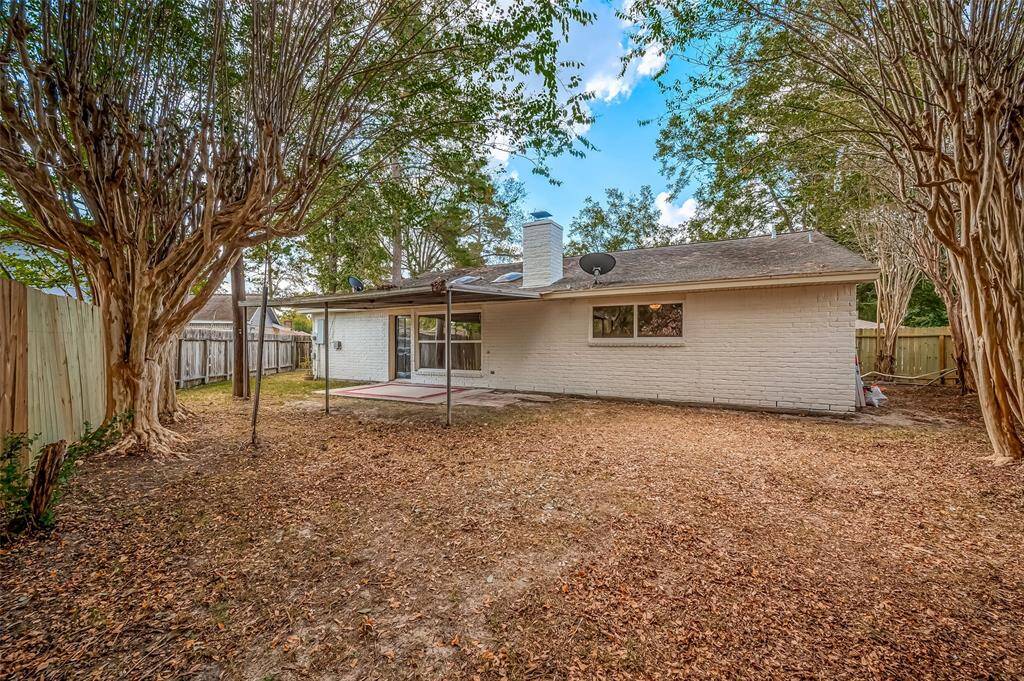 This is a single-story, brick-finished home featuring a spacious, fenced backyard with mature trees and a covered patio, offering a private outdoor space for relaxation or entertainment.