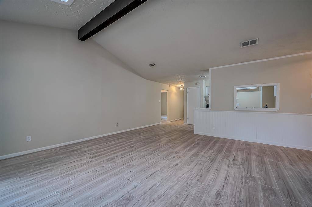 Spacious and well-lit room with contemporary wood-look flooring and neutral wall colors.  The space is versatile and ready for personalization.