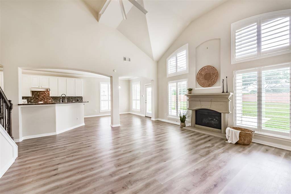 Light and bright Den with cast stone fireplace & custom plantation style shutters on the windows.
