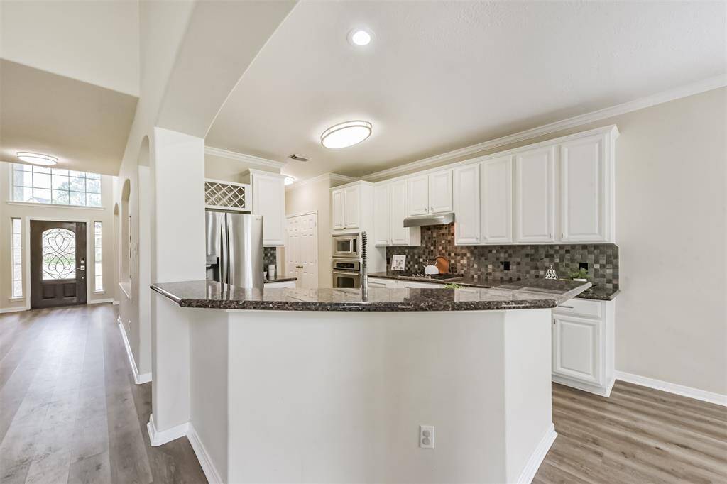 Kitchen updated with granite, wine rack above refrigerator.