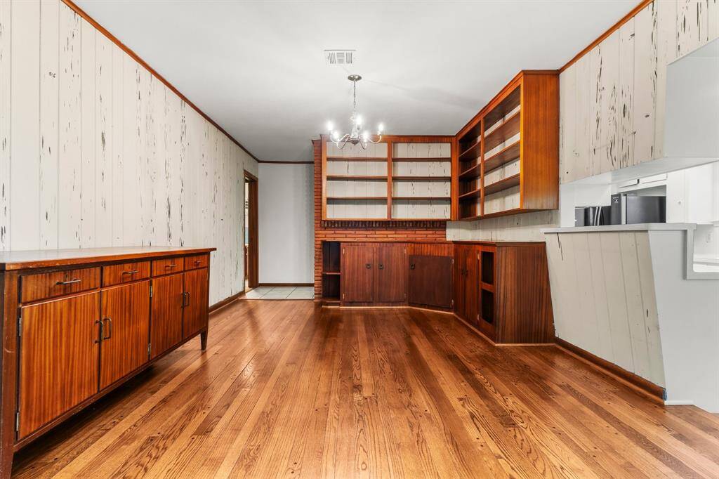 Dining Room showcases pegged hardwood floors and cypress wood walls. The sideboard and cabinets allow plenty of storage space with extra shelves for displaying items! Notice the pass-through window into the kitchen.