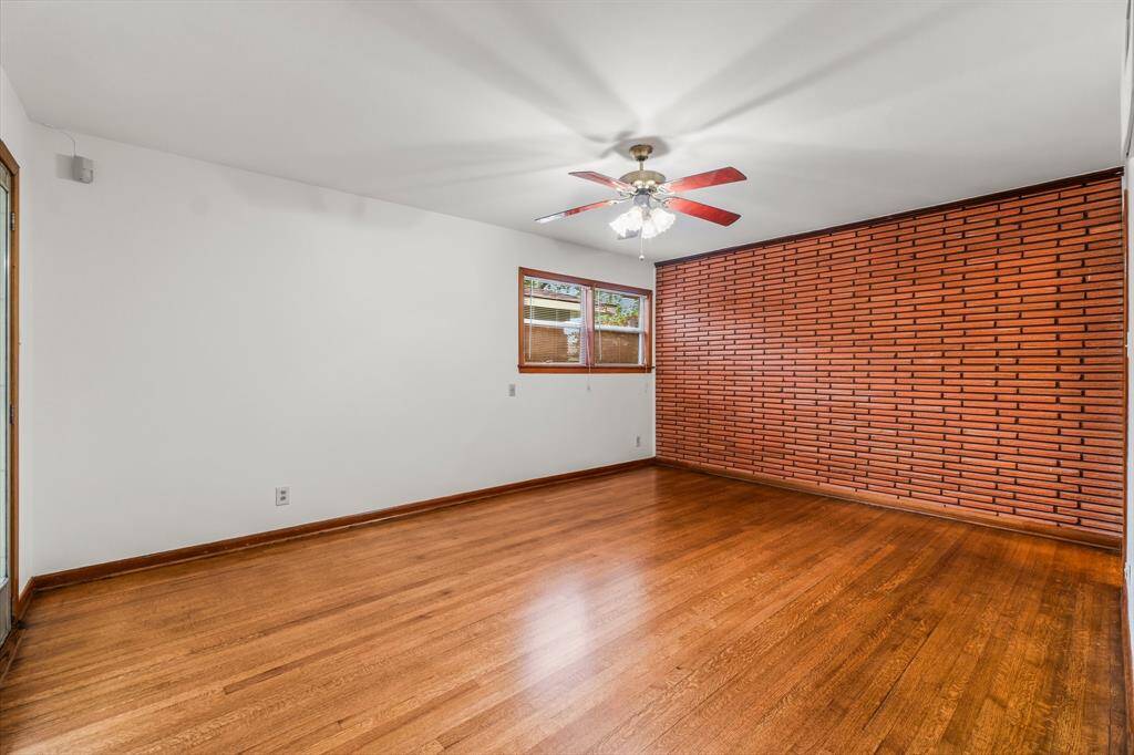 Large Primary Bedroom with ensuite bath - Notice the gorgeous hardwood floors and brick accent wall! Walls have been freshly painted in a neutral color. Door on left leads to the backyard!