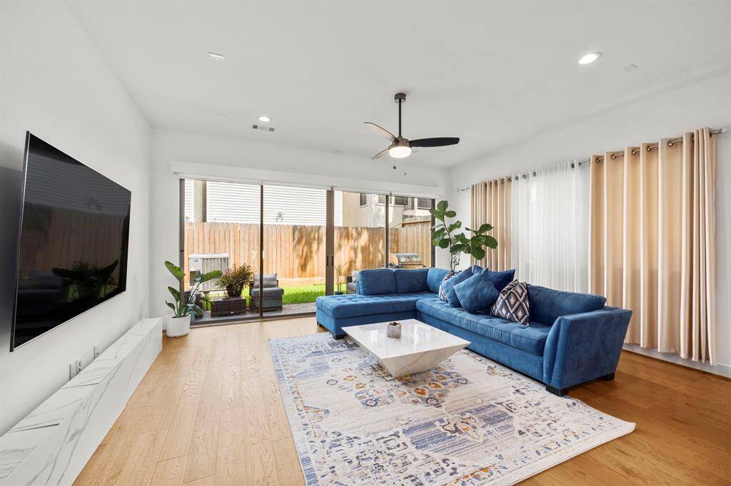 This spacious living room is filled with natural light, thanks to the floor-to-ceiling sliding glass doors that provide a seamless connection to the outdoor patio. The room's open layout offers plenty of space for relaxation and entertainment, while the large windows enhance the indoor-outdoor living experience, perfect for enjoying the backyard or hosting gatherings.