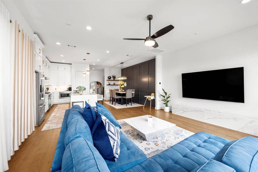 This expansive open-concept layout highlights the seamless flow between the living area, dining space, and kitchen, creating an ideal setting for both entertaining and everyday living. With clean lines, recessed lighting, and large windows, the room is filled with natural light, enhancing its bright and airy feel.