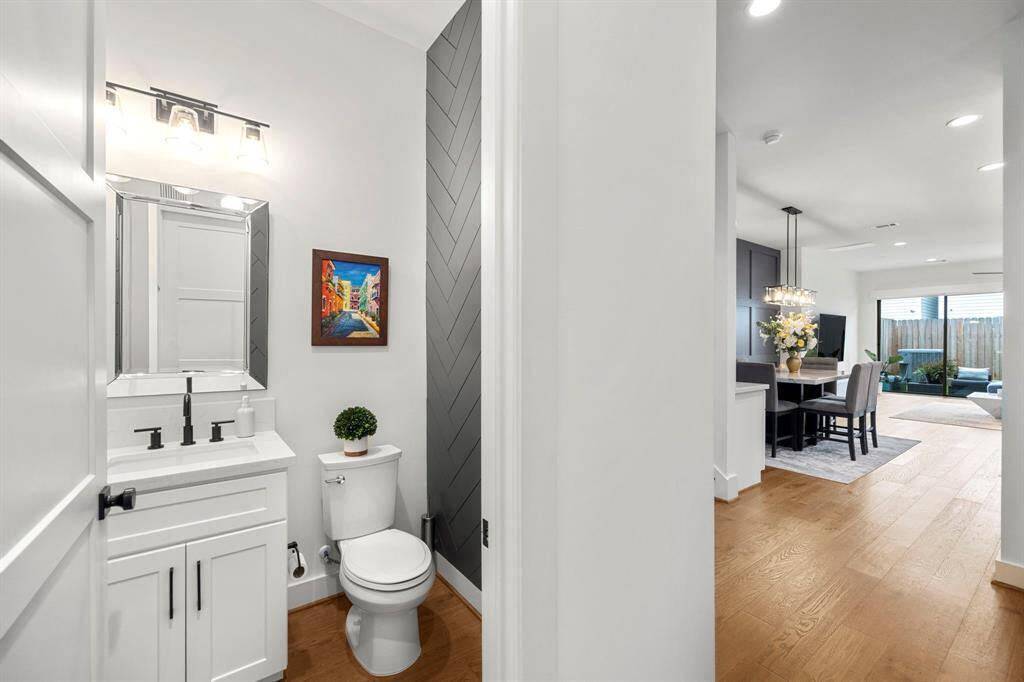 This first-floor powder room, conveniently located near the entryway and staircase, features a modern design with a sleek vanity and matte black fixtures. The chevron accent wall adds a touch of style, making this compact space both functional and visually appealing.