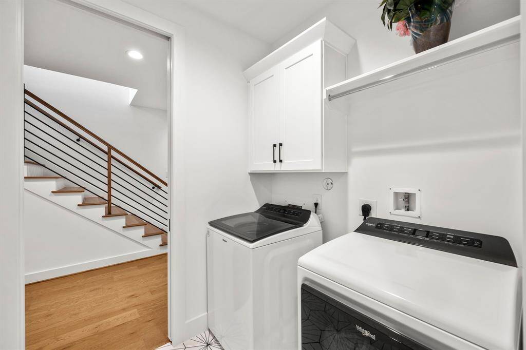 This second-floor laundry room offers convenience and efficiency with a spacious layout, including upper cabinetry for storage and a hanging rod for added functionality. The sleek design and easy access from the stairway make household chores a breeze in this well-appointed space.