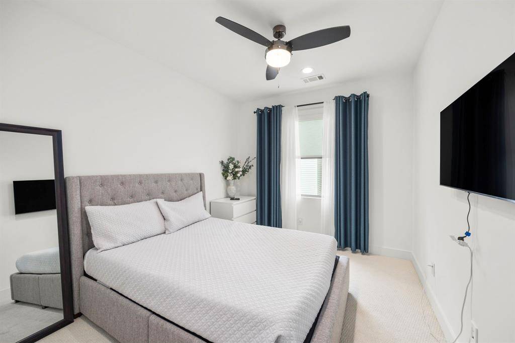 The secondary bedroom offers a cozy and bright space with natural light flowing in from the window. The room features neutral tones and a modern ceiling fan, creating a comfortable and peaceful environment. Ideal for a guest room or additional bedroom, the space is simple yet elegant with soft carpet underfoot.