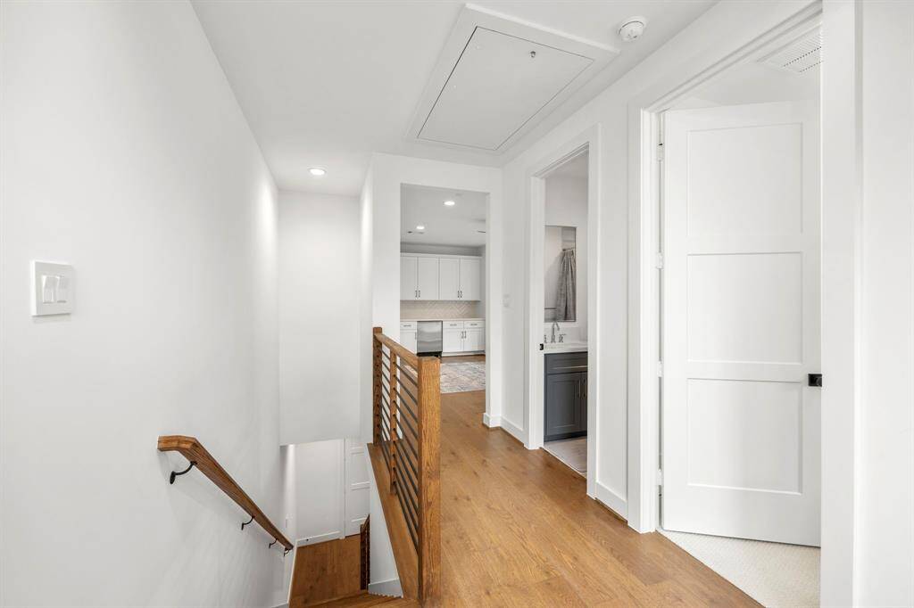 The third-floor landing offers a bright, clean space with wood floors and modern handrails leading up the staircase. The hallway connects to a secondary bedroom, media room/flex space, and a bathroom, providing easy access to additional bedrooms and bathrooms, making this floor both functional and stylish.