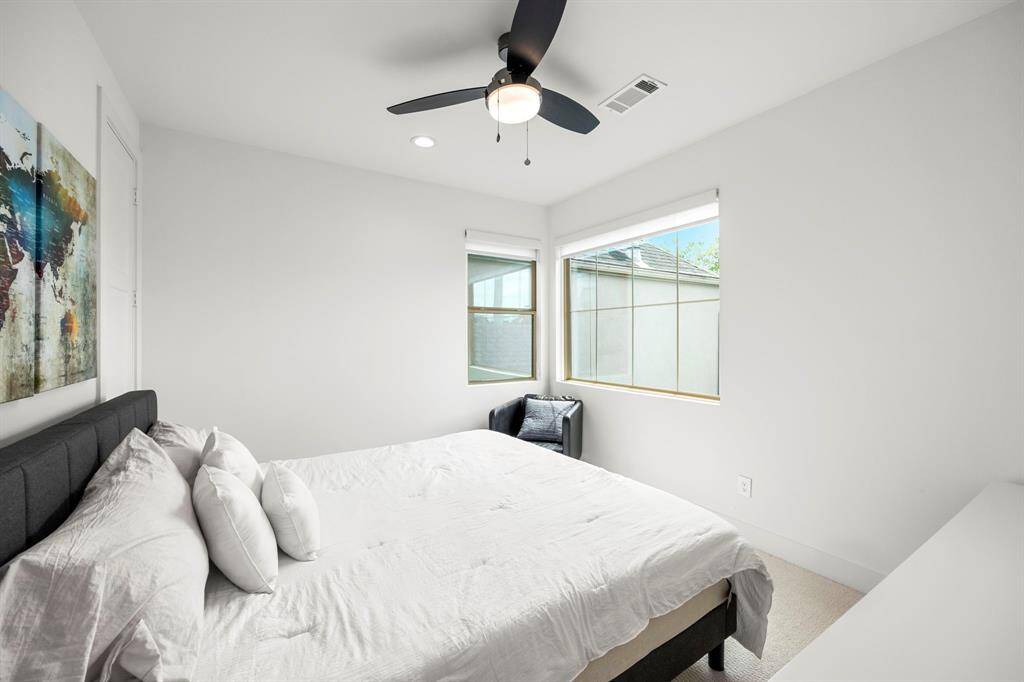 Secondary bedroom with two large windows allowing plenty of natural light, complementing the clean white walls. A ceiling fan adds both function and a modern touch to this cozy space.
