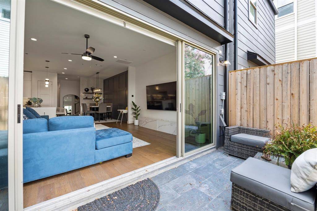 The patio area extends directly from the living room, providing an effortless transition between indoor and outdoor spaces. With sleek sliding glass doors and a tiled floor, this outdoor space is both practical and stylish, perfect for lounging or entertaining. The privacy fence adds a secluded atmosphere, enhancing the outdoor living experience.