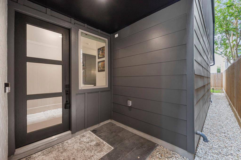 This private front entryway welcomes you with sleek modern finishes, a stylish black front door with glass inserts, and convenient side access. The minimalist design is complemented by a durable stone floor, creating an inviting yet low-maintenance entrance to the home.