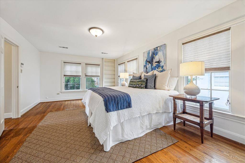 The spacious primary with pretty wood floors and a multitude of windows.