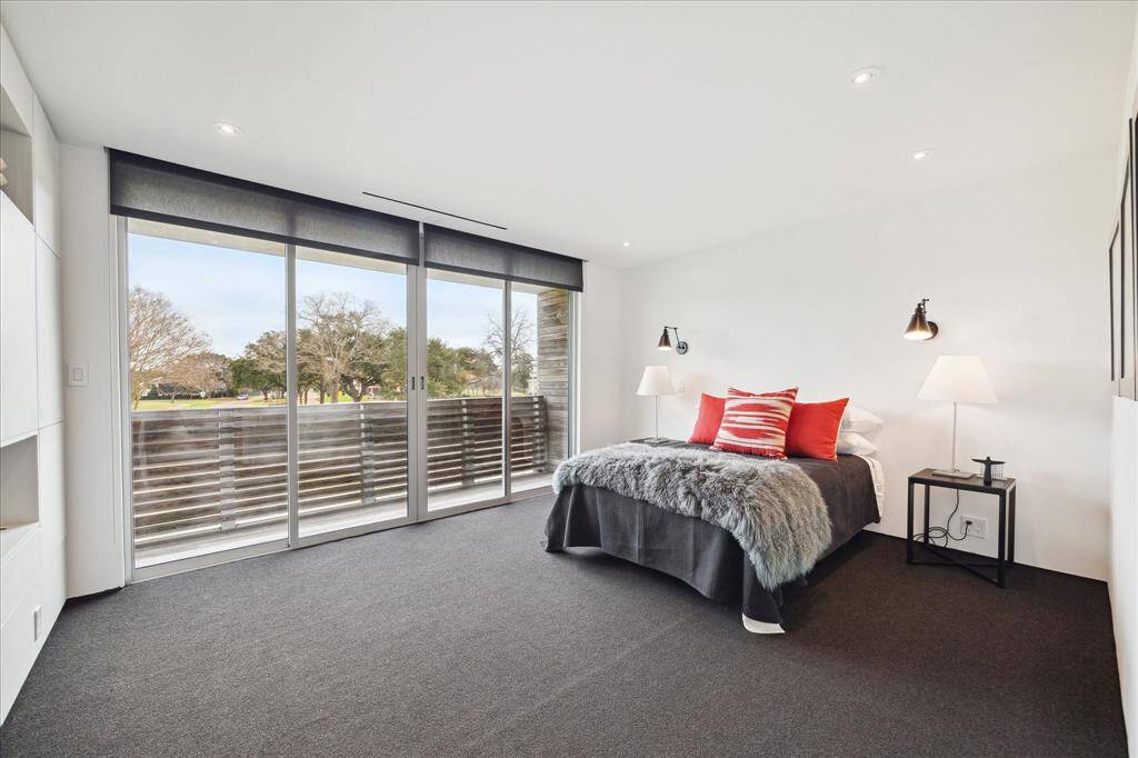 Primary bedroom with private balcony, custom window treatments and built-ins.