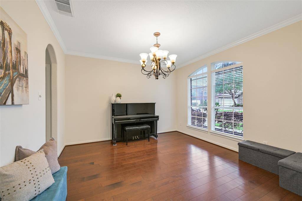 An elegant and inviting formal dining room is located just off of the foyer, featuring engineered wood floors, crown molding, a scrolled iron chandelier direct kitchen access, and a large front-facing window with arched transoms that fill the space with natural light.