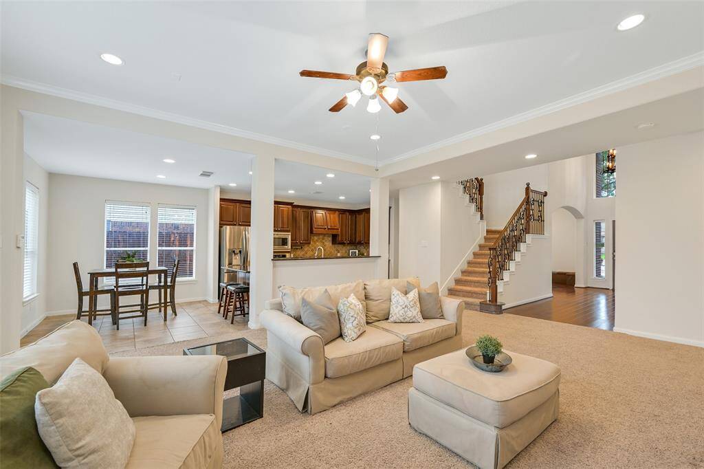 This open-concept layout seamlessly connects the family room, breakfast area, and kitchen, with views of the wrought-iron staircase and a two-story foyer. Perfect for gatherings, the space balances warmth and function with abundant natural light and easy flow for entertaining.