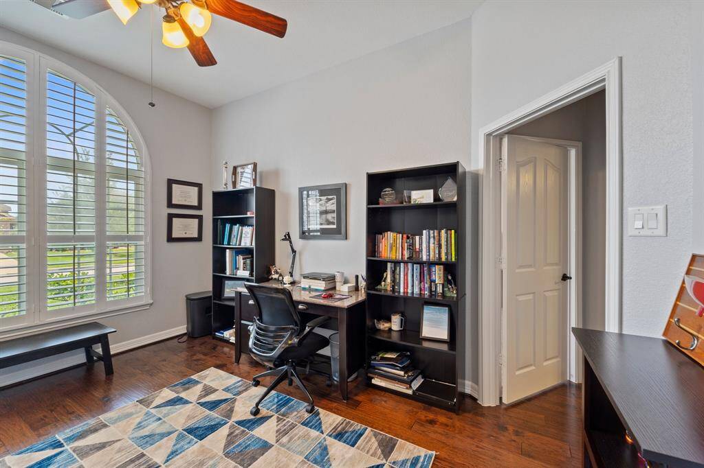 Nestled quietly in the front of the house is the handsome home office! Featuring dark stained wood floors, large windows with shutters, and a ceiling fan.