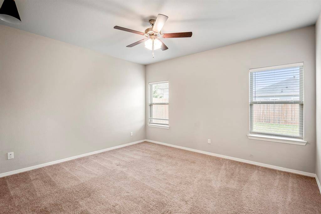 Primary Bedroom features lush carpet, natural light, and a ceiling fan.