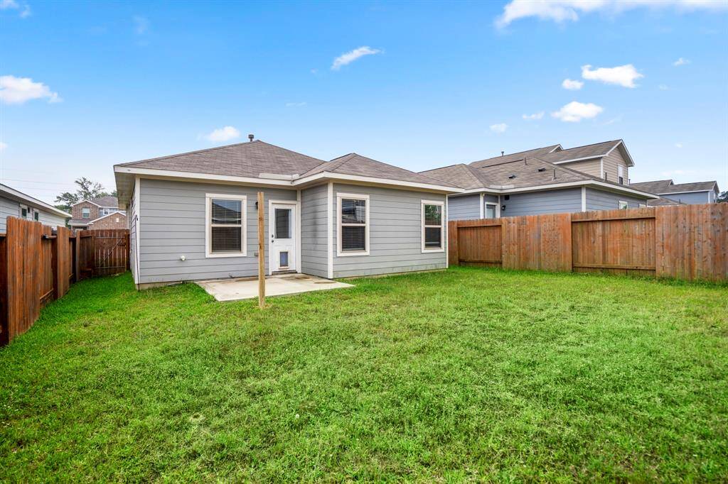 Large backyard with plenty of green space, patio has a removable cover for enjoying the weather outside.