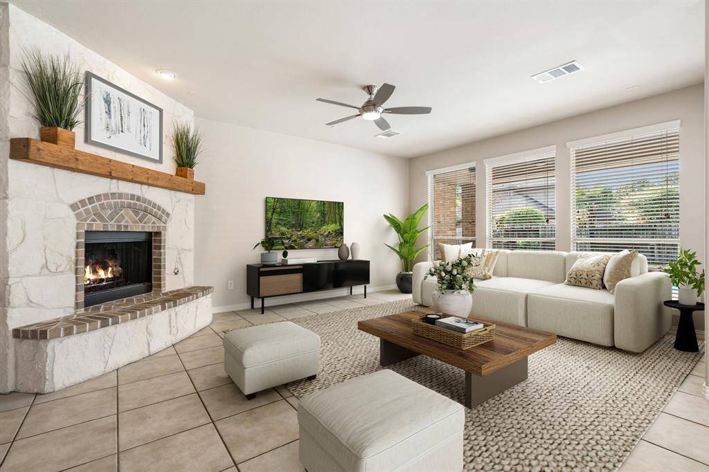 Stage living room with gas log fireplace, ceiling fan and views of the backyard pool and covered patio.