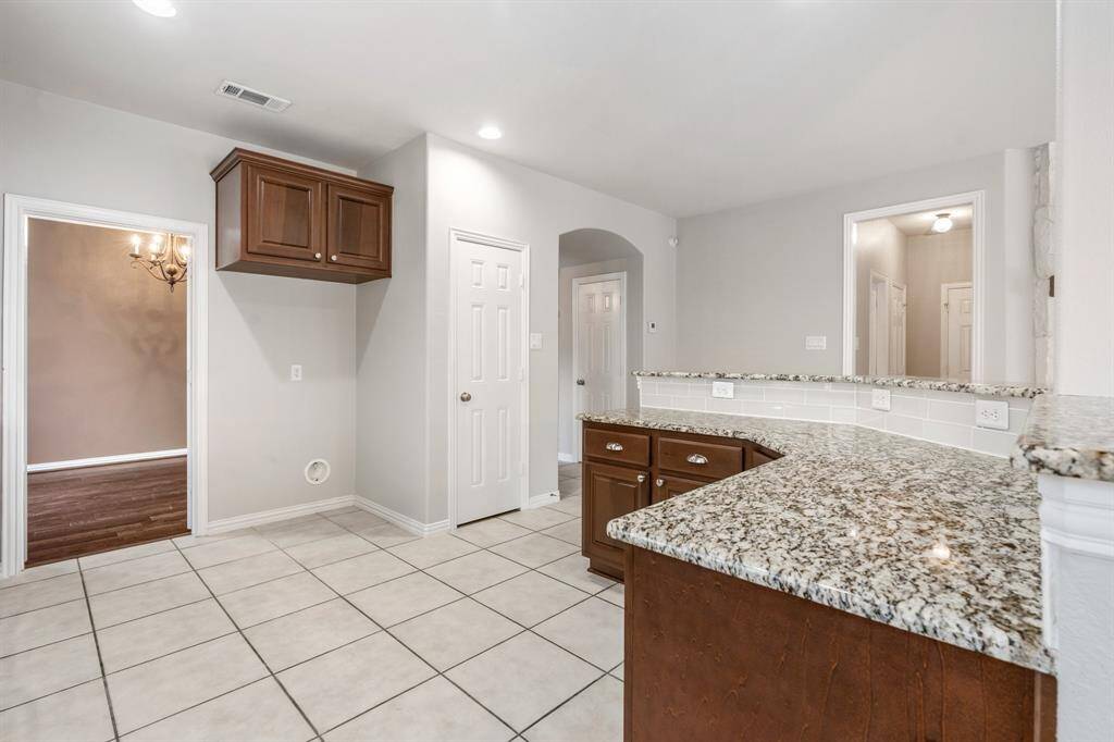 A view of the kitchen island, dining room on the left and the door on the right leads to the half bath, 2 storage closets and the primarty suite.